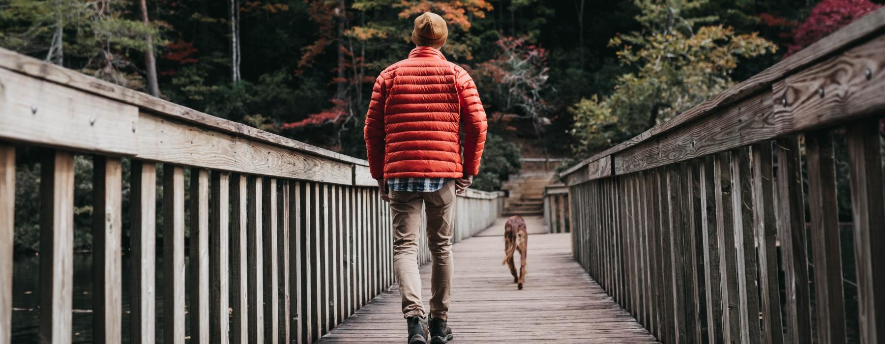 a man walking a dog on a bridge